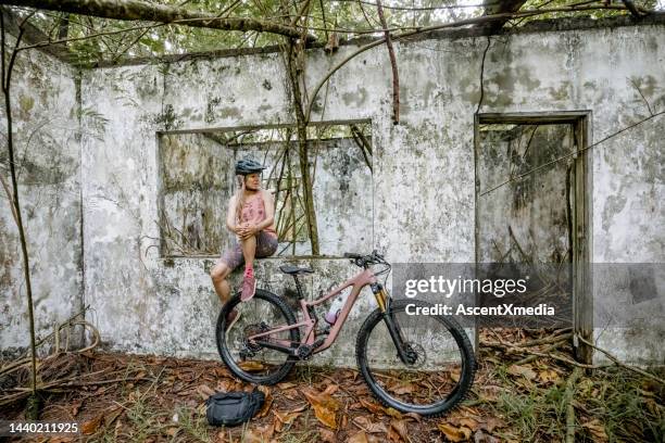 mountain biker woman sits in old building - reclaimed land stock pictures, royalty-free photos & images