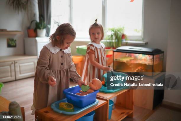 children play in montessori center together. girl child with down syndrome washes doll in basin. - bad kids classroom stockfoto's en -beelden