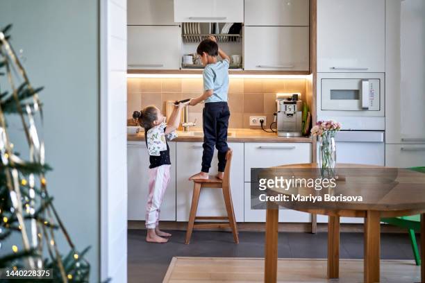 the sister helps her brother to put clean dishes in place. - kitchen after party foto e immagini stock