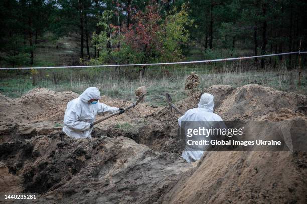 Forensic technicians with shovels exhume in trench at the site of a mass burial on October 11, 2022 in Lyman, Ukraine. The exhumation was completed...