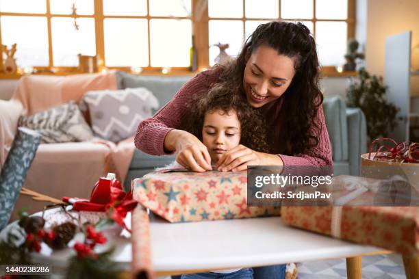 figlia con la madre che confeziona e decora i regali di natale - avvolgere foto e immagini stock