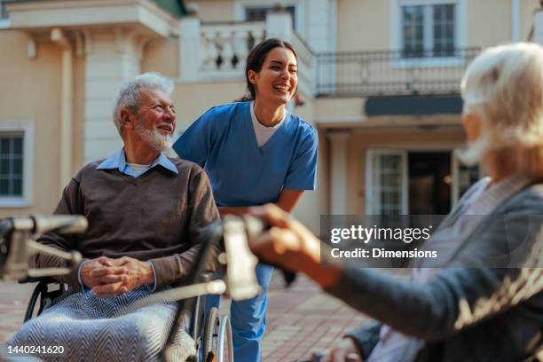 cuidador alegre y pacientes al aire libre. - hospital staff fotografías e imágenes de stock