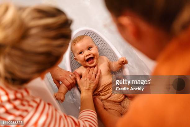 female gay couple bathing baby in bathtub - bad relationship stockfoto's en -beelden