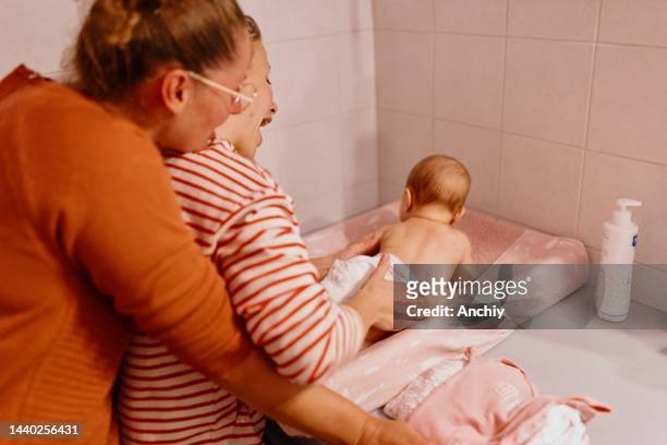 mother massaging her baby girl in the bathroom after bathing - cute lesbian couples stockfoto's en -beelden