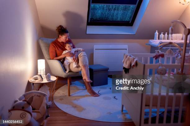mother holding baby in the nursery - nursery night stock pictures, royalty-free photos & images