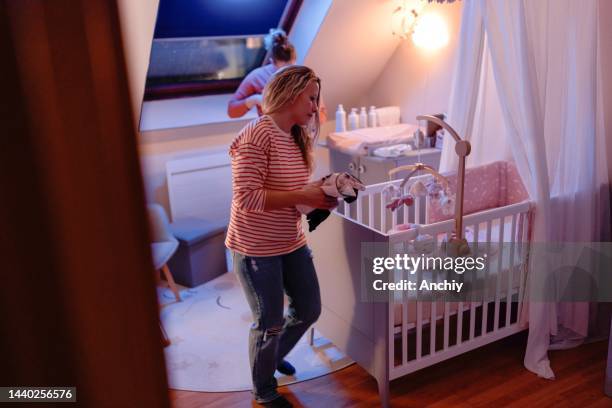 couple putting baby to sleep in the nursery - nursery night stock pictures, royalty-free photos & images