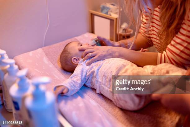 woman uses nasal aspirator for her baby girl at home - suction tube stock pictures, royalty-free photos & images