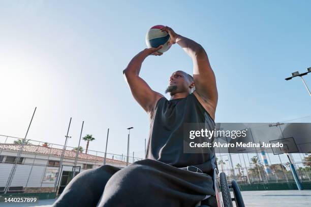 african american male wheelchair basketball player shooting basket on an outdoor court. - athlète handicapé photos et images de collection