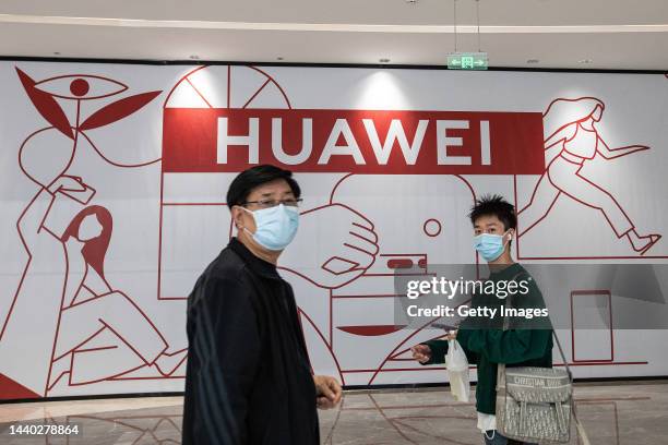 Visitors walk past a Huawei store preparing to open at the Wushang Dream Plaza mall as the world's largest single shopping mall opens with 800,000...