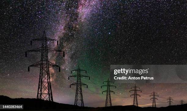 high voltage towers on the background of the starry sky. power outage, blackout - corriente-de-alto-voltaje fotografías e imágenes de stock