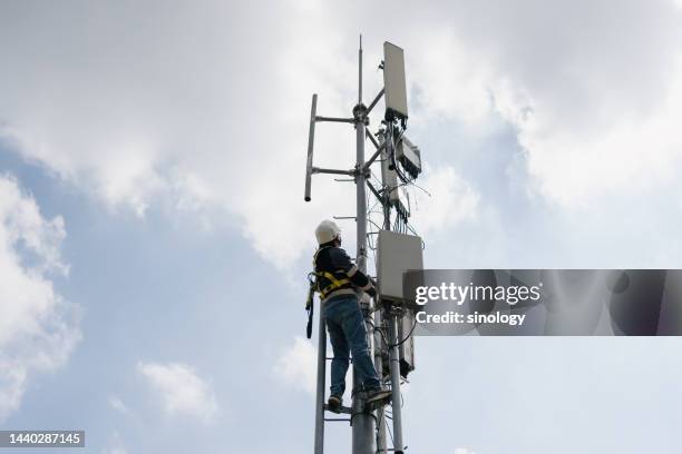 worker is installing 5g telecommunication base station - repeater tower stock-fotos und bilder