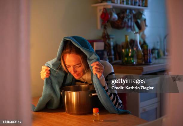 woman inhaling over pot with hot water as a cold remedy - erkältung stock-fotos und bilder