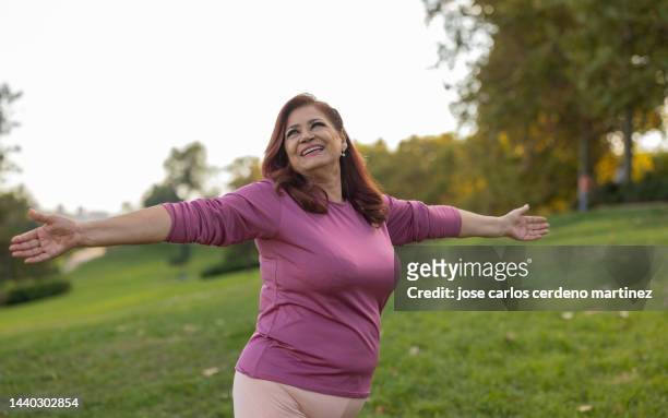 senior curvy woman with red hair with outstretched arms enjoying in the nature. - fat old lady stock pictures, royalty-free photos & images
