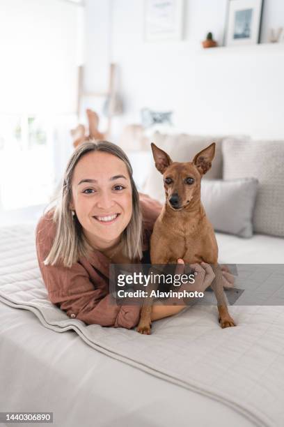 young woman with her dog on the bed in her room - doberman puppy stock pictures, royalty-free photos & images
