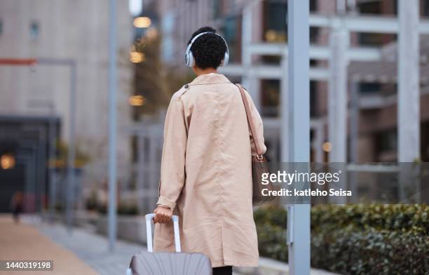 travel, business woman and walking in a city, listening to music on her way to a meeting in new york. corporate employee traveling to conference with luggage, enjoying motivation audio podcast - york hotel stock pictures, royalty-free photos & images
