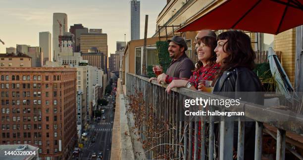 friends looking out at sunset on urban balcony - los angeles garden party stock pictures, royalty-free photos & images