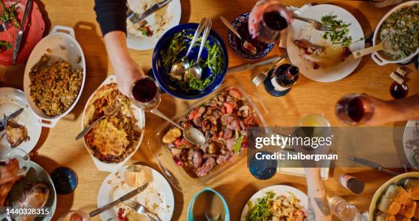 scatto dall'alto verso il basso degli ospiti che alzano i bicchieri al tavolo da pranzo del ringraziamento - ospite foto e immagini stock