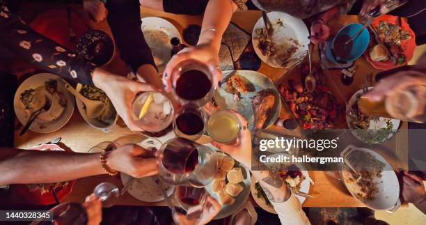 scatto ad alta angolazione degli ospiti che brindano al tavolo da pranzo del ringraziamento - ospite foto e immagini stock