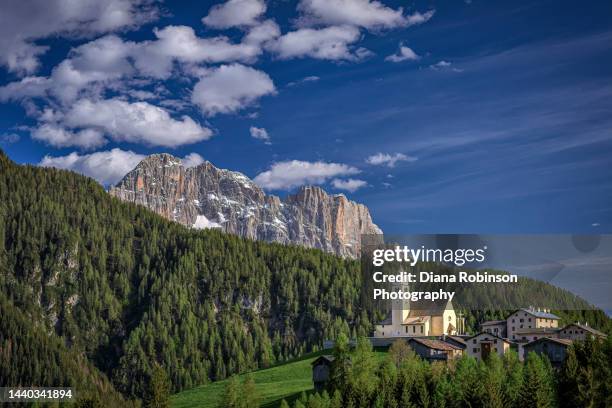 an ancient church on top of a hill in colle santa lucia in the province of belluno in the italian region of veneto is dedicated to saint lucy.  it is pictured here with the view over the pelmo and civetta mountains of the veneto dolomites - colle santa lucia stock pictures, royalty-free photos & images