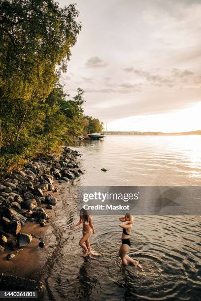 high angle view of female friends enjoying vacation at lake during sunset - stockholm beach stock pictures, royalty-free photos & images