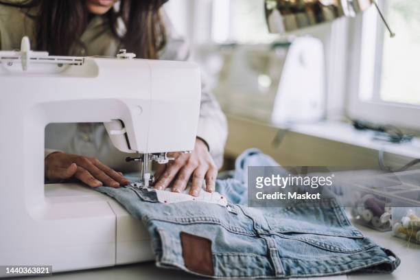 midsection of female design professional stitching fabric through sewing machine at workshop - sewing foto e immagini stock