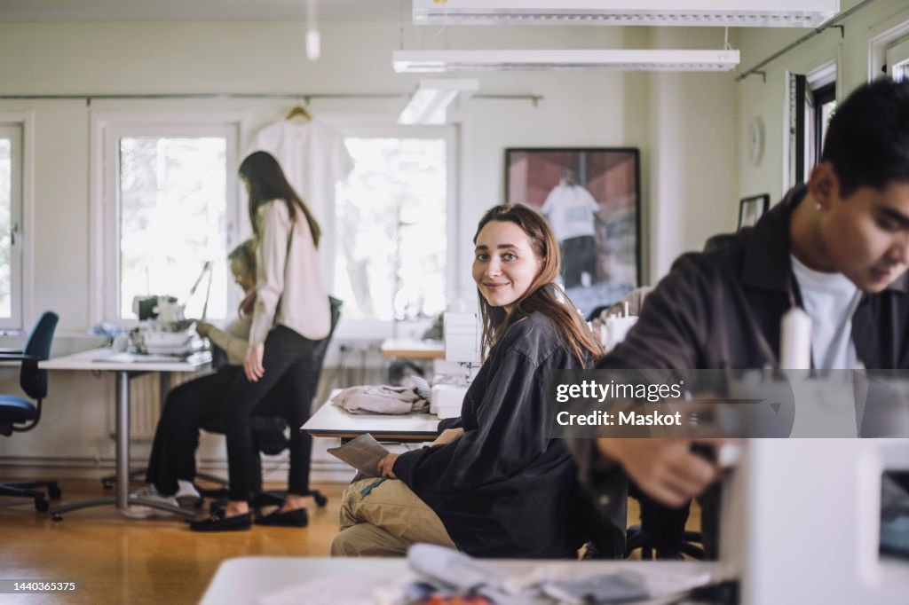 Portrait of smiling female fashion designer sitting at workshop