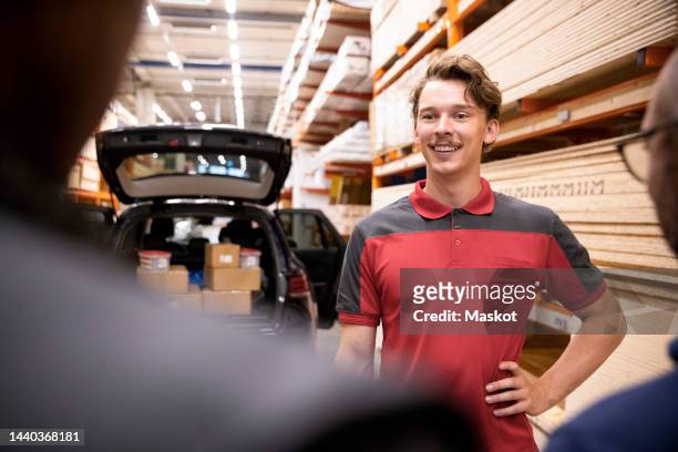 smiling salesman with hand on hip talking with customer at hardware store - car salesman stock pictures, royalty-free photos & images