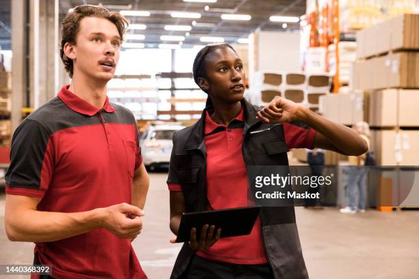 saleswoman holding digital tablet while discussing with male staff at hardware store - salesman ストックフォトと画像