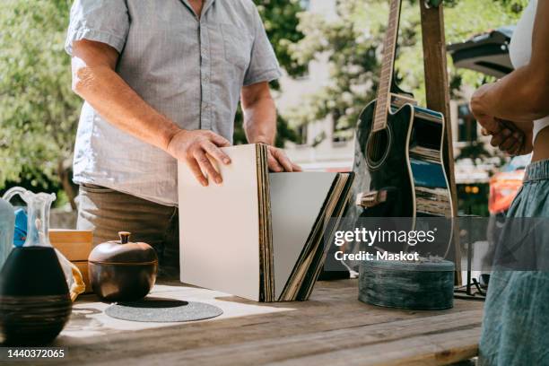 midsection of male customer buying records at flea market - flea market stockfoto's en -beelden