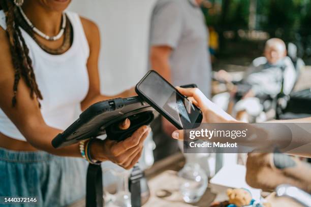 hand of woman doing contactless payment while shopping at flea market - brand name mobile payment photos et images de collection