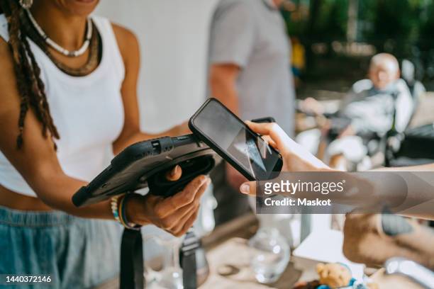 hand of woman doing contactless payment while shopping at flea market - apple pay stock pictures, royalty-free photos & images