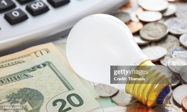 a light bulb, us dollar bills and a calculator - electricity bill stock pictures, royalty-free photos & images