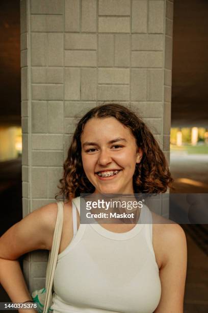 portrait of happy teenage girl with medium-length hair against column - teenagers only stock pictures, royalty-free photos & images