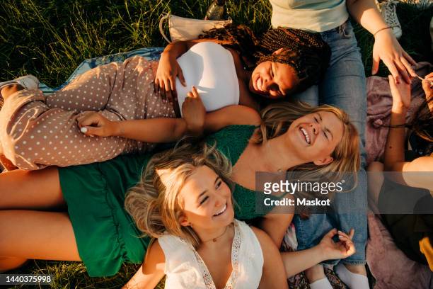 high angle view of cheerful friends laughing while lying down at park - girl lying down stock pictures, royalty-free photos & images