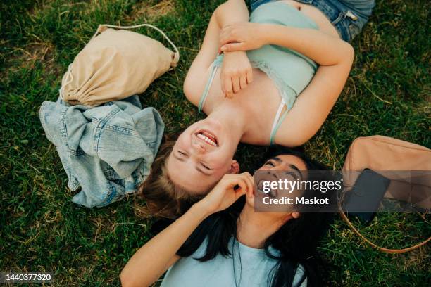 cheerful teenage girls lying together at park - arab people laugh stockfoto's en -beelden