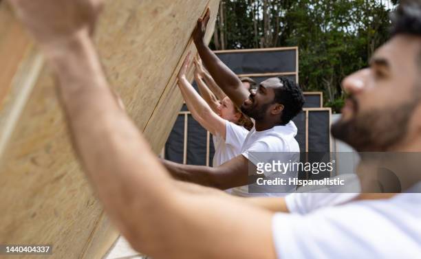 happy group of volunteers working together building a house - habitat for humanity stock pictures, royalty-free photos & images