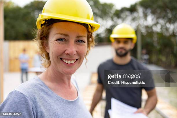 femme heureuse travaillant dans l’industrie de la construction et souriante - ouvrier maçon photos et images de collection