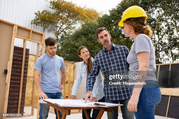 project manager talking to his team about the blueprints at a construction site - welfare reform stock pictures, royalty-free photos & images