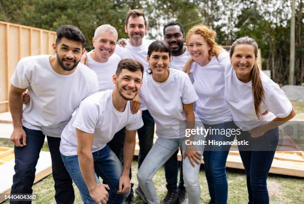 un joyeux groupe de bénévoles souriants sur un chantier de construction - t shirt photos et images de collection