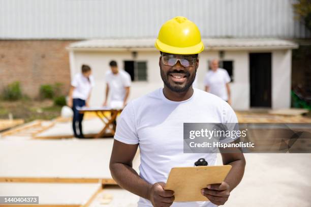 happy man volunteering to build a house and working as a project manager - habitat for humanity stock pictures, royalty-free photos & images