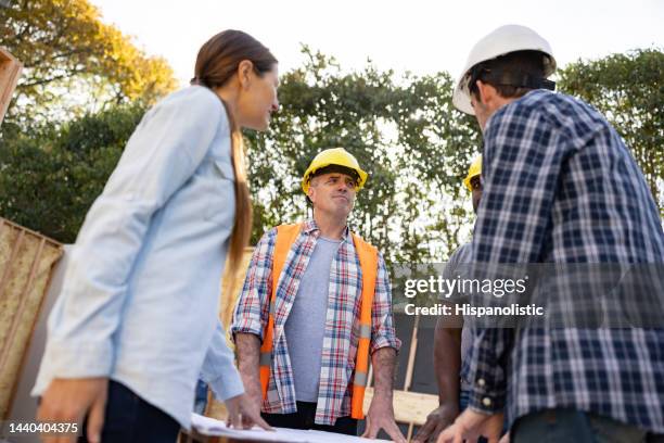 architects having a meeting with his clients at a construction site - construction meeting helmet stock pictures, royalty-free photos & images