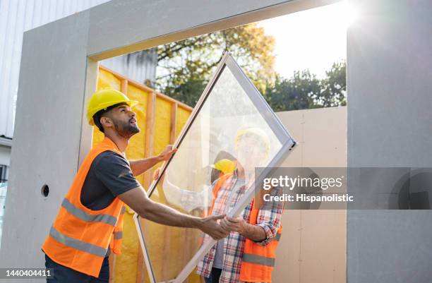 two workers at a construction site installing a window - window installation stock pictures, royalty-free photos & images