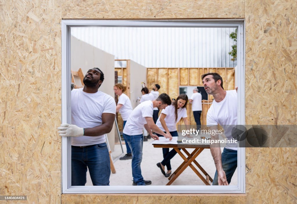 Volunteers installing a window while building a house