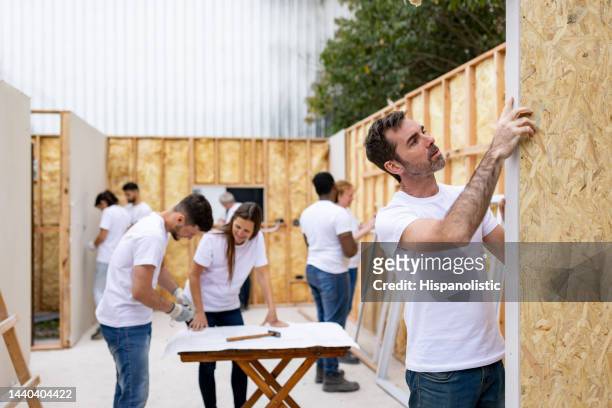 group of volunteers building a house - habitat for humanity stock pictures, royalty-free photos & images