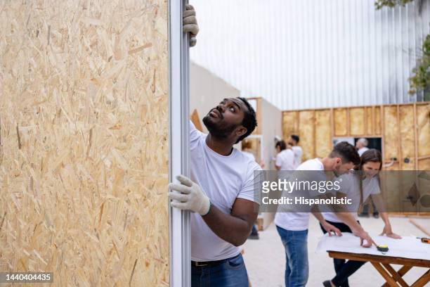freiwilliger beim einbau eines fensters beim bau eines hauses - mobile home stock-fotos und bilder