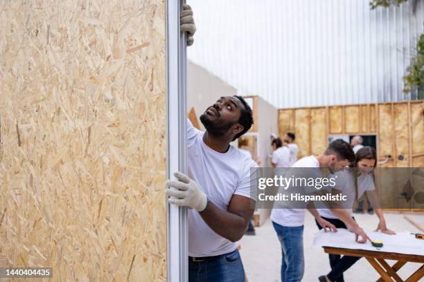 volunteer installing a window while building a house - herbouwen stockfoto's en -beelden