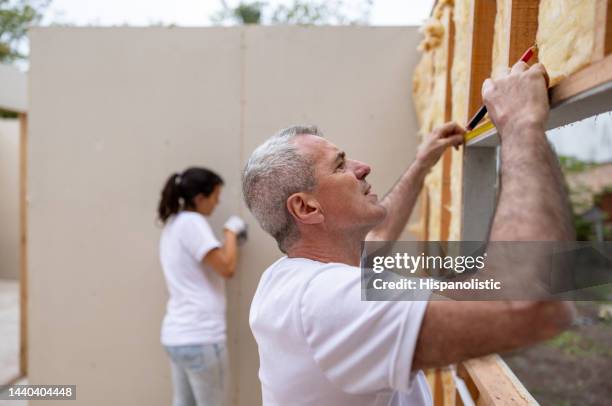 volunteer installing a window while building a house - habitat for humanity stock pictures, royalty-free photos & images