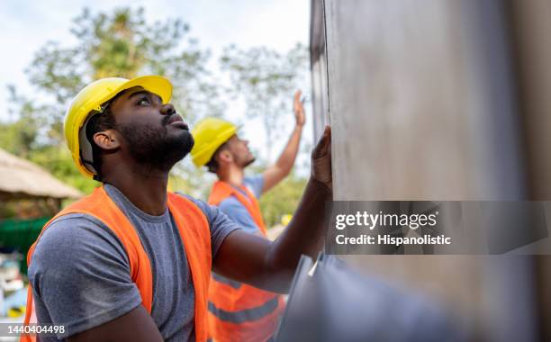 travailleurs de la construction installant des panneaux lors de la construction d’une maison usinée - ouvrier du bâtiment photos et images de collection