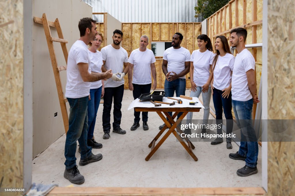 Group of volunteers in a meeting while building a house for charity