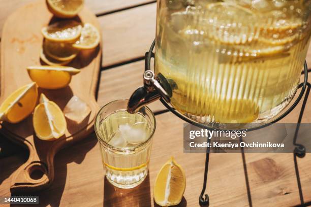 lemonade with ice in a pitcher and glass on a wooden table with fruit and crushed ice outside with a lemon field in the background on a sunny day. front view. horizontal composition. - sorbet isolated stock pictures, royalty-free photos & images